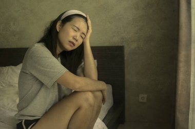 Genç, üzgün ve üzgün Asyalı bir kız. Saç bandında evde oturuyor. Düşünceli ve endişeli. 