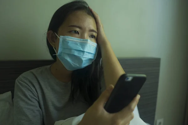 パンデミックとウイルス発生 若い美しい怖がって心配アジアの女性は 隔離された自宅でベッドのロックダウン時に携帯電話でオンラインニュースをチェック — ストック写真