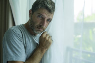 Orta yaşlı bir adamın hüzünlü ve depresif bir şekilde ağlayan iç mekan portresi. Evde umutsuzluk içinde, endişeli ve bunalım ve endişe dolu bir depresyon ve endişe dolu bir perde tutuyor.