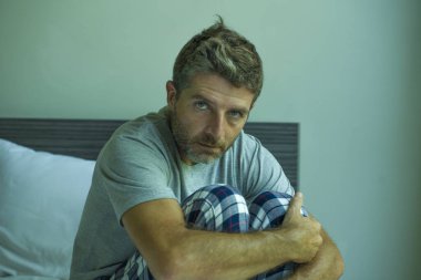 Çekici, korkmuş ve depresyonda olan 40 'lı yaşlarda pijamalı bir adamın dramatik portresi virüs karantinası sırasında endişe ve depresyon sorunu yaşıyor.