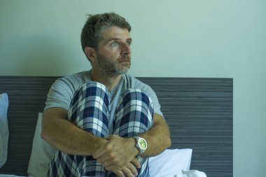 Çekici, korkmuş ve depresyonda olan 40 'lı yaşlarda pijamalı bir adamın dramatik portresi virüs karantinası sırasında endişe ve depresyon sorunu yaşıyor.