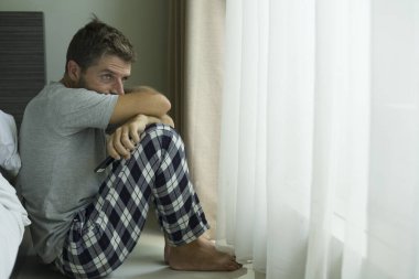 Çekici, korkmuş ve depresyonda olan 40 'lı yaşlarda pijamalı bir adamın dramatik portresi virüs karantinası sırasında endişe ve depresyon sorunu yaşıyor.