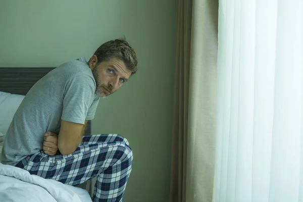 dramatic portrait of attractive scared and depressed 40s man on bed in pajamas feeling worried suffering anxiety and depression problem during virus quarantine home lockdown