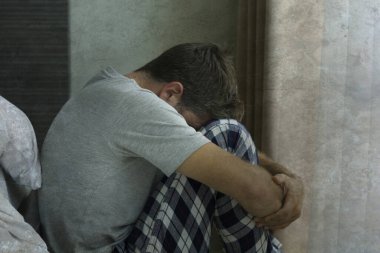 Çekici, korkmuş ve depresyonda olan 40 'lı yaşlarda pijamalı bir adamın dramatik portresi virüs karantinası sırasında endişe ve depresyon sorunu yaşıyor.