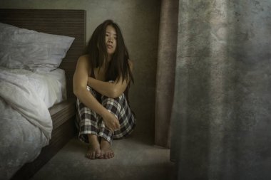 Depresyondaki ve üzgün Asyalı Koreli kadının dramatik karanlık portresi. Endişeli ve korkmuş. Depresyon sorunu ve yatağa yaslanma korkusu.