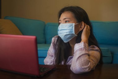 quarantine and home lockdown - young beautiful worried and scared Asian Korean woman working or studying with laptop computer during covid-19 virus outbreak clipart