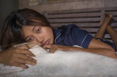 Karantina evindeki virüs salgını sırasında acı ve korku içinde yatan üzgün ve endişeli genç ve korkmuş Asyalı kadının dramatik yaşam tarzı portresi.