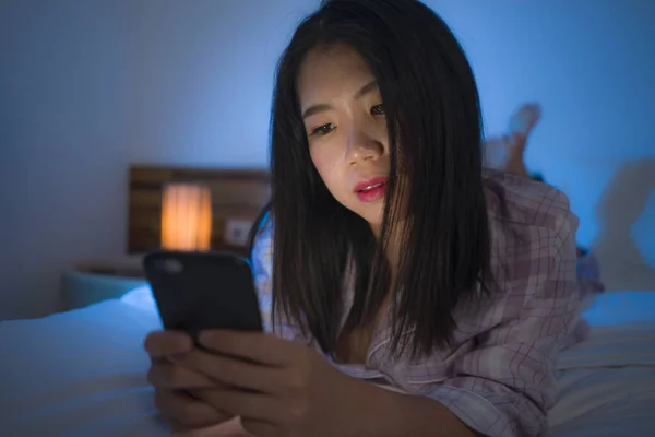 若いです美しいとリラックスしたアジアの女性のライフスタイルの肖像上のベッドの上で携帯電話で遊ぶ上のベッドの上で暗いでインターネット中毒やソーシャルメディアの強迫観念と乱用 — ストック写真