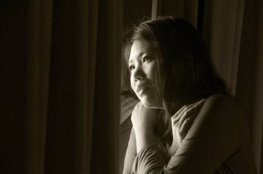 Genç, güzel, korkmuş ve depresif Asyalı bir kadının karanlık dramatik portresi. Bunalmış ve panik içinde evde tek başına virüslü karantina sırasında.