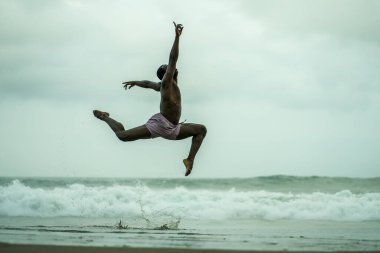Çağdaş dans koreografı ve dansçısı, bale sahili egzersizi yapıyor. Genç, çekici ve atletik siyahi Afrikalı Amerikalı erkek dışarıda dans ediyor. Dramatik bir performans sergiliyor. 