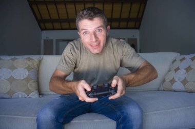 Evde video oyunları oynayan, video oyunları oynayan, video oyunu bağımlılığı ve teknoloji manyağı kavramının keyfini çıkaran genç ve heyecanlı bir adamın kapalı bir portresi.