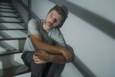 Depresyonda olan üzgün ve çaresiz bir adamın korku filmi portresi ya da evdeki merdivenlerde oturan umutsuz, çaresiz ve bunalmış bir adamın portresi.