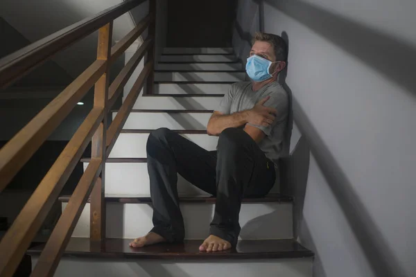 在昏暗的画像中 身穿防护面具 害怕而又忧心忡忡的年轻人 在家中楼梯上坐着 在昏暗的光线下 为19型弧菌病毒大流行进行检疫 — 图库照片