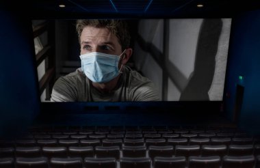 2020 COVID-19 virüslü boş sinema projeksiyonunun kavramsal kurgu görüntüsü koruyucu maskeli adamı karantina evindeki kilit altında gösteriyor.