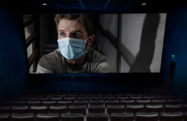 2020年Covid 19病毒爆发时空旷电影院放映电影的概念小说形象屏幕上的男子戴着防护面具被隔离在家里 — 图库照片