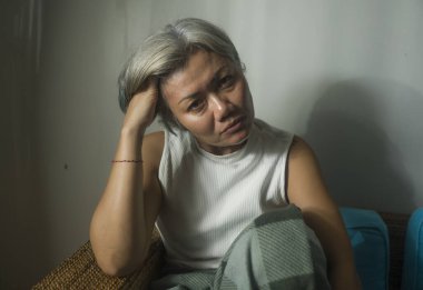 Çekici, üzgün ve endişeli olgun bir kadın oturma odasındaki kanepede depresyonda ve korkmuş orta yaş bunalımı ve korku içinde yalnız başına ev hapsinde tutuluyor.