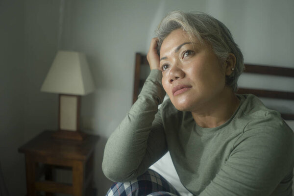mature lady crisis - attractive middle aged woman with grey hair sad and depressed in bed feeling scared and lonely thinking worried about covid-19 virus pandemic during home lockdown