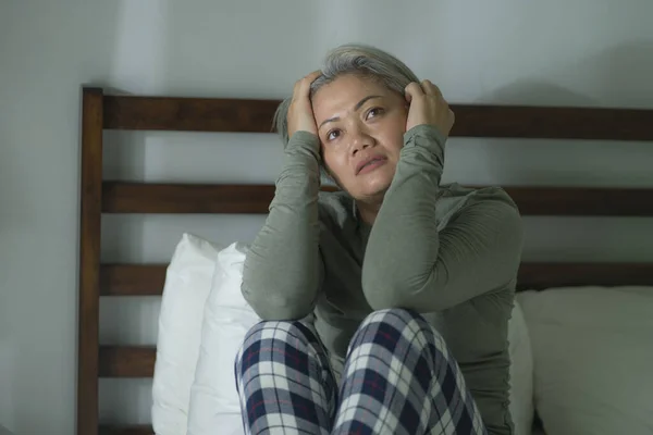 mature lady crisis - indoors lifestyle portrait of middle aged woman with grey hair sad and depressed in bed feeling frustrated and lonely thinking about aging lonely suffering depression