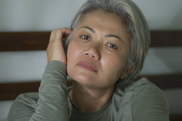 mature lady crisis - indoors lifestyle portrait of middle aged woman with grey hair sad and depressed in bed feeling frustrated and lonely thinking about aging lonely suffering depression 