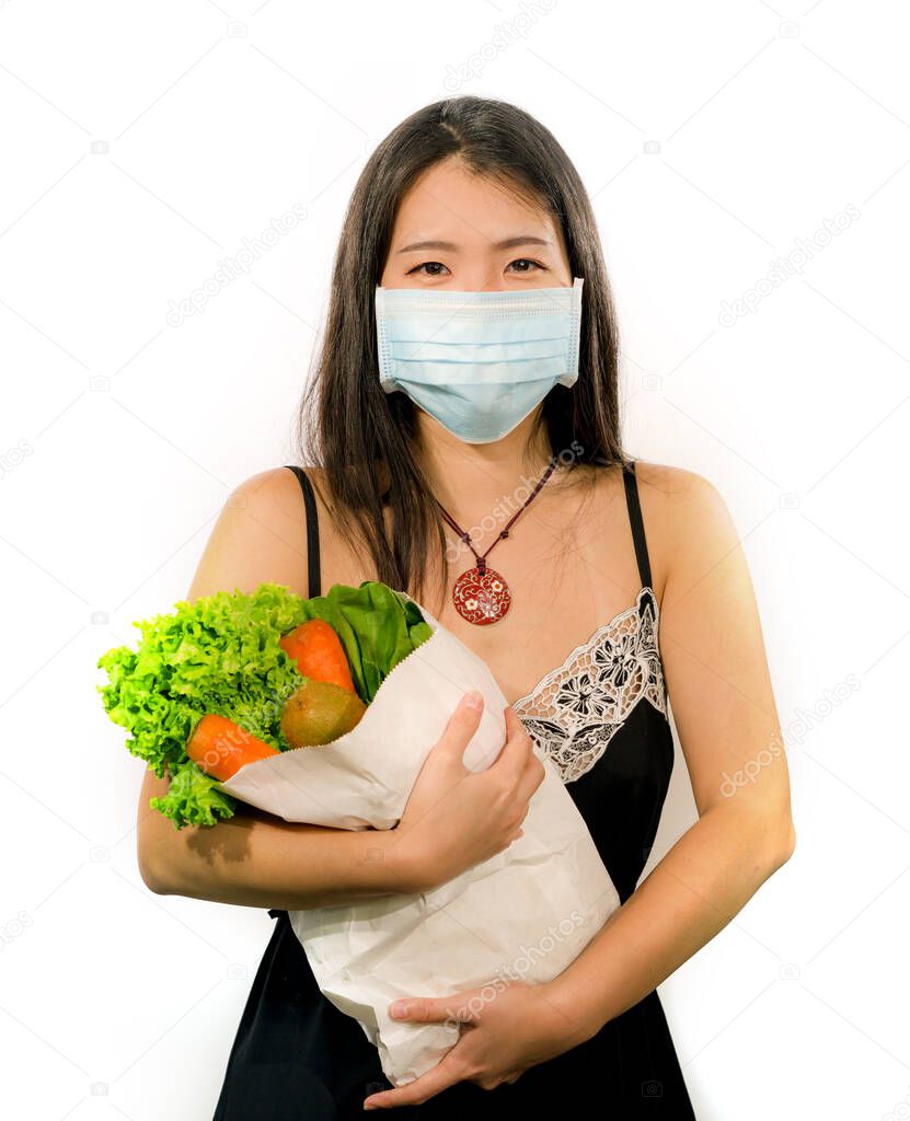 food groceries shooping during covid-19 virus quarantine and home lockdown - young beautiful happy and positive Asian Korean woman in face mask carrying bag with vegetables smiling