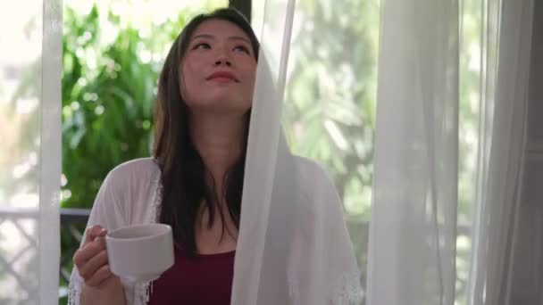 아름다운 아시아 출신의 테라스 문에서 커피나 마시거나 편안하고 모습의 발코니에서 — 비디오