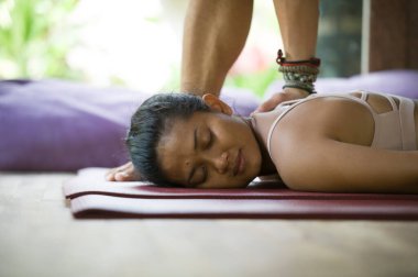 Genç, çekici ve formda bir masör güzel ve rahat Asyalı bir kadına geleneksel Tayland masajı yapıyor. Stüdyoda yatıyor ve tropikal kaplıcalarda tedavi görüyor. 