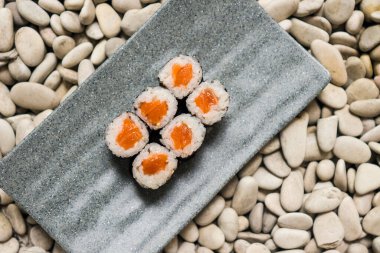 Japon gurme mutfağı - lezzetli ve narin Japon suşi yemeği geleneksel sağlıklı Asya yemekleri ve yaratıcı doğulu yemek kavramının taş zemin üzerinde yuvarlanıyor.