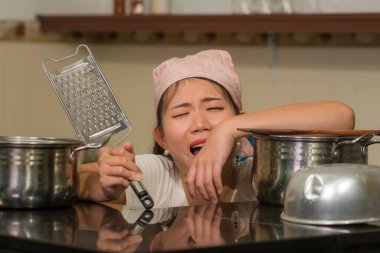 lifestyle home portrait of beautiful overwhelmed and stressed Korean girl working in kitchen unhappy and upset housekeeping - young frustrated Asian woman screaming in domestic chores stress  clipart