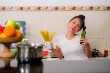 Çekici ve mutlu Asyalı kadın erişte hazırlıyor. Ev yapımı tatlı ve eğlenceli Çinli kızın ev yapımı portresi. Mutfakta makarna pişiriyor.