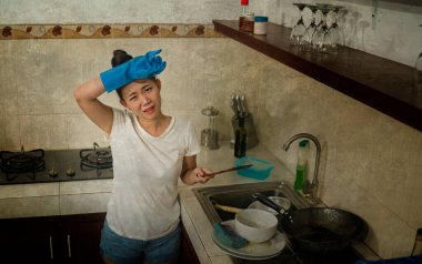 Genç, hayal kırıklığına uğramış ve ev işleri yapan Asyalı bir kadın. Sevimli, bunalmış ve stresli bir Çinli kız. Mutfak temizliğinde bulaşık yıkıyor.