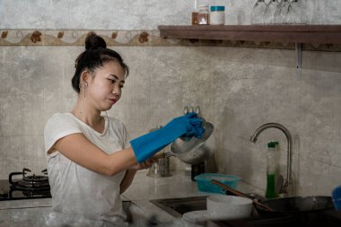 Genç, hayal kırıklığına uğramış, ev işleri yapan Asyalı bir kadın. Sevimli, bunalmış ve stresli bir Japon kız. Mutfak temizliğinde bulaşık yıkıyor.