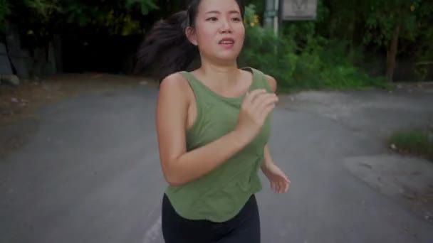 屋外ランニングワークアウト 若い幸せと献身的なアジアの女性が美しい都市公園や田舎道でジョギングしながら健康的なライフスタイルでフィットネスを楽しむジンバルトラッキング — ストック動画