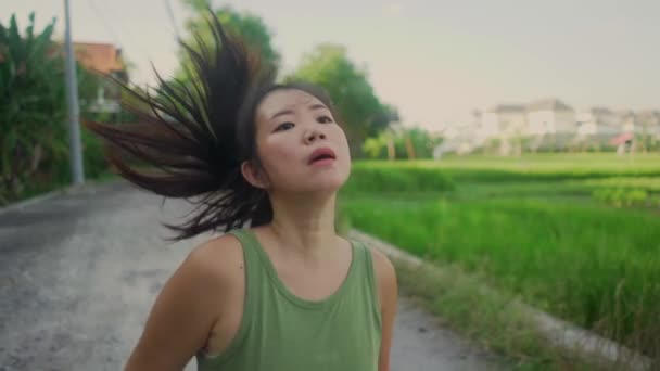 屋外ランニングワークアウト スローモーショントラッキングジンバル若い幸せと献身的なアジアの中国人女性フィットネスや心臓活動を楽しむ美しい都市公園や田舎道でジョギング — ストック動画