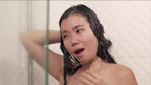 若い美しいと幸せなアジアの女性のライフスタイルショットバスルームでシャワーを浴びて彼女の髪を洗う自宅で朝の衛生ルーチンを楽しんで — ストック動画