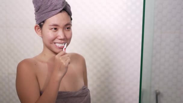 domácí životní styl záběr mladých šťastný a krásný asijský číňan žena čištění zubů na hlavě ručník zábal v koupelně zrcadlo veselý a uvolněný v kráse a hygieny koncept