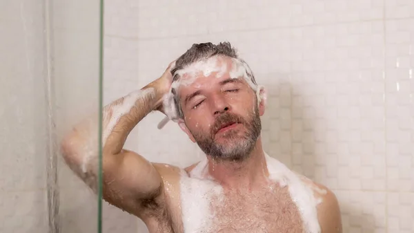 朝のシャワー 若い魅力的で幸せな男のライフスタイルの肖像画ひげを生やしてシャワーを浴びて自宅でシャンプーで彼の髪を洗う健康と衛生の概念で陽気に楽しむ — ストック写真