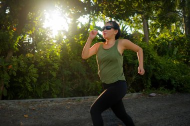 Açık havada koşmak - genç mutlu ve kendini Asya 'ya adamış Koreli bir kadın güzel şehir parkında ya da gün batımında spor yapıyor sağlıklı yaşam tarzında spor ve kardiyo aktivitelerinin keyfini çıkarıyor.