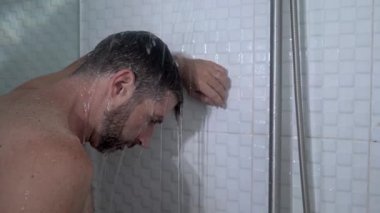 Evde banyo dramatik bir şekilde genç, çekici, üzgün ve depresif bir adamın duşta duvara yaslanmış düşünceli bir şekilde hayat sorununun altında ezildiği bir sahne. 