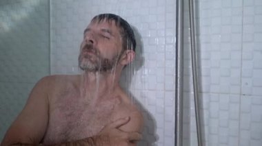 Evde banyo dramatik bir şekilde genç, çekici, üzgün ve depresif bir adamın duşta duvara yaslanmış düşünceli bir şekilde hayat sorununun altında ezildiği bir sahne. 