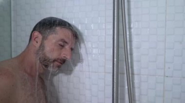 Evde banyo dramatik portresi. Duşta üzgün ve depresif genç bir adam. Duvara yaslanmış düşünceli bir duygu. 