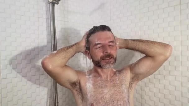 若い魅力的で幸せな男髭を生やしてシャワーを浴びて家でシャンプーで髪を洗う陽気に健康と衛生の概念で朝のシャワーを楽しんで — ストック動画