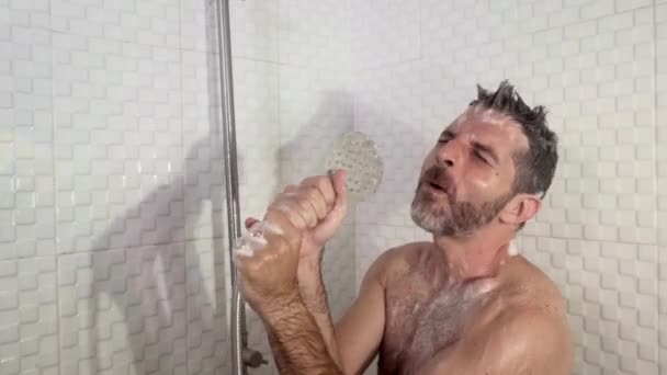 年轻迷人而快乐的男人 留着胡子 无忧无虑地在浴室里跳舞唱歌 在家里疯狂地假装拿着话筒 享受着 — 图库视频影像