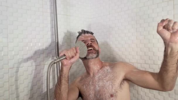 미소짓는 매력적 수염을 기르고 집에서 마이크 체하며 샤워기 안에서 노래를 — 비디오