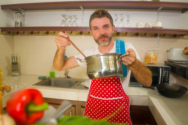 Jovem Bonito Feliz Homem Avental Vermelho Segurando Panela Cozinha Sorrindo — Fotografia de Stock