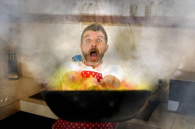 Mutfakta felaket bir aşçı. Önlük giymiş, çaresiz ve komik bir adam. Stres ve korku içinde tavayı tutuyor.