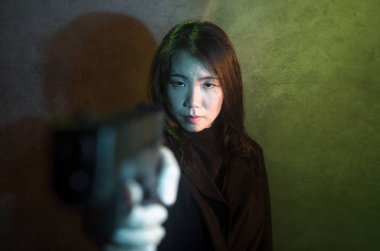 Çekici ve tehlikeli bir kadın ajanın ya da elinde tabanca olan Asyalı bir gangsterin, Hollywood film tarzında ateşli bir şekilde silahını doğrultmuş sinemalı bir portresi.
