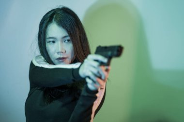Çekici ve tehlikeli bir kadın ajanın ya da elinde tabanca olan Asyalı bir gangsterin, Hollywood film tarzında ateşli bir şekilde silahını doğrultmuş sinemalı bir portresi.