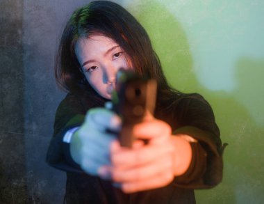 Çekici ve tehlikeli bir kadın ajanın ya da elinde tabanca olan Asyalı bir gangsterin, Hollywood film tarzında ateşli bir şekilde silahını doğrultmuş sinemalı bir portresi.