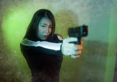 Çekici ve tehlikeli bir kadın ajanın ya da elinde tabanca olan Asyalı bir gangsterin, Hollywood film tarzında ateşli bir şekilde silahını doğrultmuş sinemalı bir portresi.
