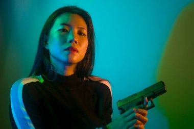 Çekici ve tehlikeli bir kadın ajanın ya da elinde tabanca olan Asyalı bir gangsterin, Hollywood film tarzında ateşli bir şekilde silahını doğrultmuş sinemalı bir portresi.